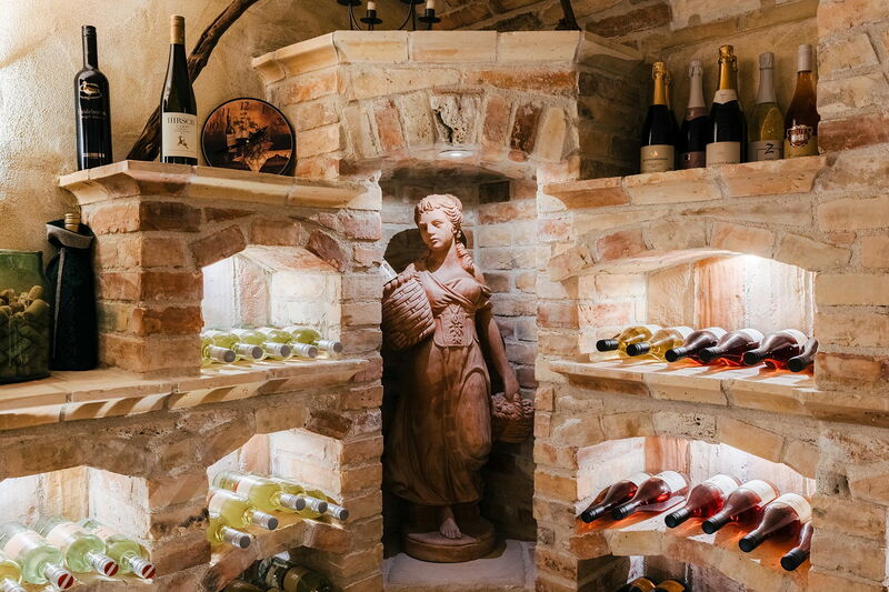 Gemauerte Weinnischen im Weinkeller mit Weißwein- und Rosé-Flaschen