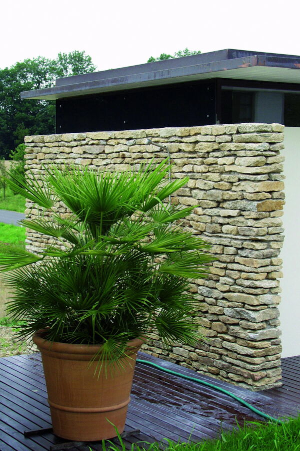 Badehaus mit Stein-Schichtmauerwerk im südländischen Flair und Gartenterrasse mit grüner Pflanze