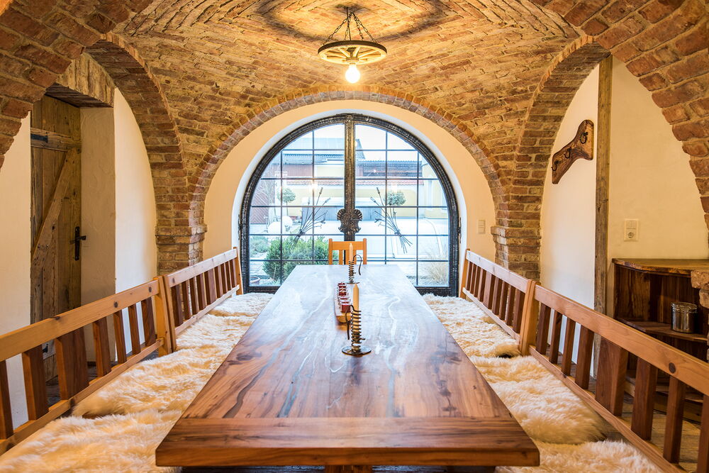 Gemütlicher Festraum mit Vollholztisch und Holzbänken unter Böhmischen Gewölbe mit Ziegelsäulen